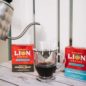 Water being poured into single serve drip coffee pouch, position over glass cup