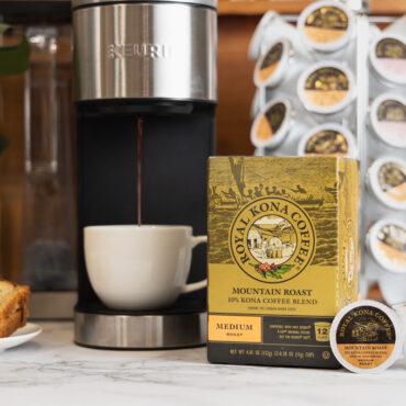 Royal Kona 10% Kona Mountain Roast Coffee Single Serve Pods next to coffee machine