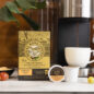 Royal Kona 10% Roy's Pacific Roast Coffee Single Serve Pods next to coffee machine